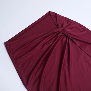Detailed close-up of burgundy lace dress featuring elegant waist twist and ruched fabric