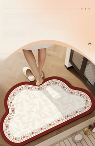 Detail of floral bathroom mat with red edges and anti-slip texture on wooden floor