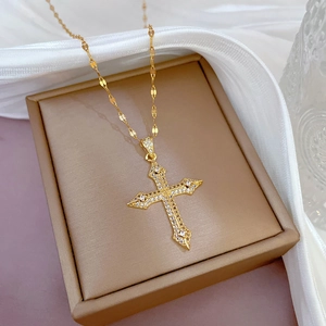 18K gold plated stainless steel cross necklace with cubic zirconia pavé on a jewelry box
