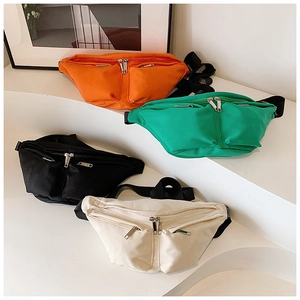 Detail of four colorful crossbody bags with wide straps on a white tiered background