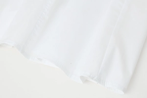 Close-up of white dress hem showing fine stitching and soft fabric texture details