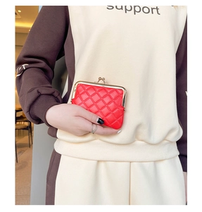 Macro shot of red quilted faux leather coin purse with golden metal kiss lock closure
