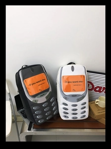 Detail of retro cellphone style backpacks in black and white finish on a bench