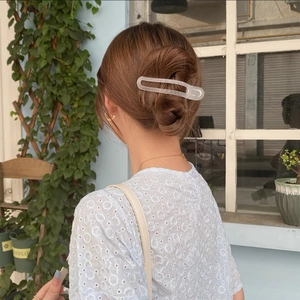 Detail view of a matte transparent hair claw clip worn on hair with natural lighting