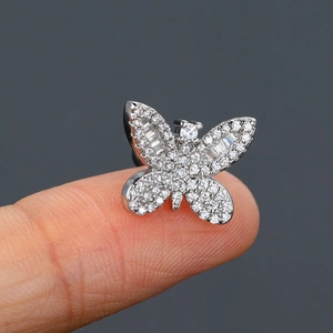 Macro shot of silver butterfly stud earring with zircon stones held on a fingertip
