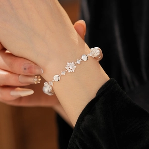 Détail d'un bracelet de perles avec fleurs en zircon et breloques flocons de neige