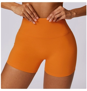 Close-up of orange high-waisted yoga shorts showing tummy control waistband and texture