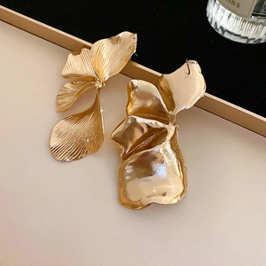 Detailed macro view of gold-finished 3D flower earrings with brushed metal texture