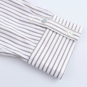 Détail des manches longues et des boutons nacrés sur une chemise en coton à rayures