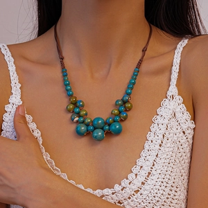 Gros plan d'un collier de perles tressé avec perles bleues et vertes sur un modèle