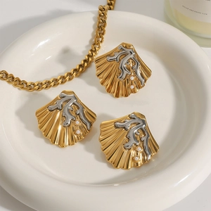 Gouden schelpensieradenset met koraalaccenten en witte parels op een wit dienblad