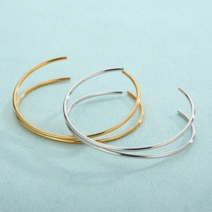 Macro shot of minimalist gold and silver titanium steel thin cuff bracelets layered together