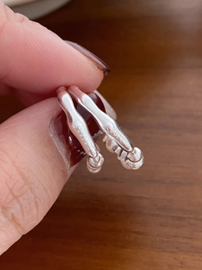Macro shot of S925 sterling silver stud earrings showing clear quality hallmark on wood