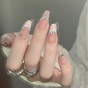 Macro shot of long trapezoid nails with pink gradient, checkerboard pattern and pearls