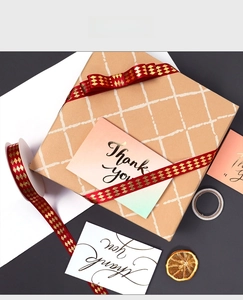 Red ribbon with gold foil diamond pattern tied in a bow on a gift box