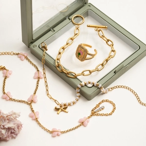 Detail showing golden chain jewelry set with pink butterflies and beaded accents on a box