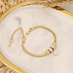 Détail d'un bracelet maille serpent doré avec disque en cristal sur marbre