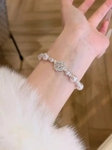 Gros plan détaillé d'un bracelet en perles avec breloque fleur en zircon au poignet