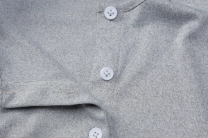 Macro shot of grey knit fabric with white four-hole buttons and fine ribbed texture