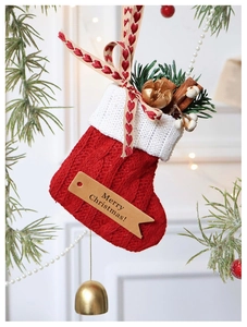 Detail of red and white knitted Christmas stocking hanging on decorative pine branches