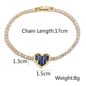 Detailed view of golden tennis bracelet with blue heart pendant and clear zircon inlay