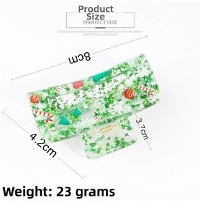Detail of an 8cm green acrylic Christmas tree hair claw with glitter and snowflake prints