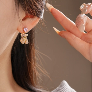 Gros plan détaillé d'une boucle d'oreille ourson avec cœur rose et cristaux brillants