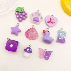 Close-up of purple resin charms including grape, cat paw, and heart for DIY jewelry