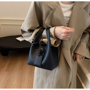 Minimalist black bucket bag with lychee pattern leather and top handle design