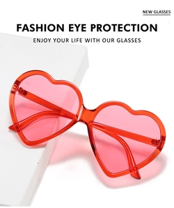 Fashion heart-shaped sunglasses in transparent red shown on a white geometric stand