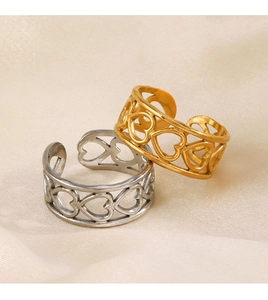 Detail of gold and silver hollow heart open rings on beige satin background