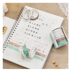 Close-up of geometric washi tape rolls on a grid notebook with dried flowers and decor