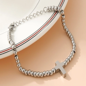 Detail of 4mm stainless steel bead bracelet with cross pendant on a white plate