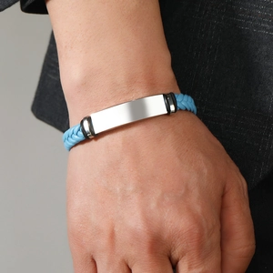 Detail of blue leather woven bracelet with silver metal bar on a suit-wearing wrist