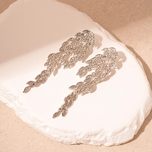 Elegant silver leaf tassel earrings with rhinestones on stone display pedestal