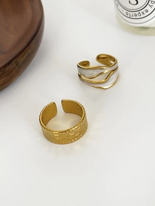 Macro detail of 18K gold pleated rings with white enamel inlay and hammered texture