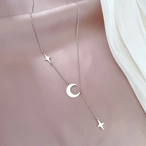 Detailed view of silver star and moon pendant necklace on soft silk background
