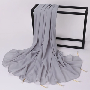Detail of gray chiffon shawl with elegant gold pearl pin and soft draped texture