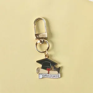 Gold graduation keychain with black academic cap and white graduate scroll pendant