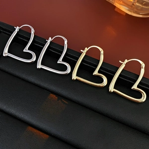 Détail de boucles d'oreilles créoles en forme de cœur avec finitions dorées et argentées
