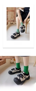 Detail of green knit mid-calf socks paired with black and white sneakers and velcro strap