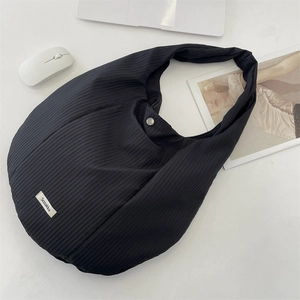 Gros plan d'un sac cabas noir à texture côtelée avec fermoir magnétique et petit logo
