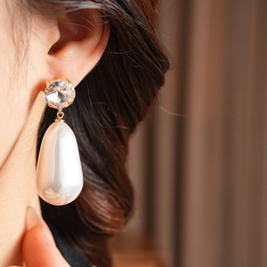 Gros plan de boucles d'oreilles pendantes perles d'eau et cristaux portées par un mannequin