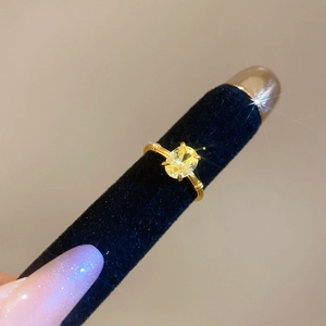 Macro shot of gold oval yellow gemstone ring with fine textured triple-layer band