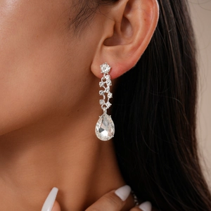 Detailed close-up of luxury V-shape teardrop diamond earrings on a model ear