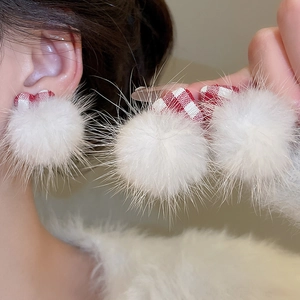 Detail of white fluffy fur ball earrings with red plaid bowknot in a sweet style