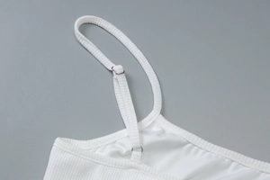 Detail view of white ribbed fabric dress with adjustable silver metal shoulder strap buckle