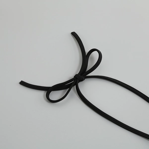Detail of a black sequin dress featuring a knit halter strap tied in a delicate bow knot