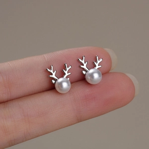 Close-up of elegant silver reindeer antler earrings with white pearls held in fingers