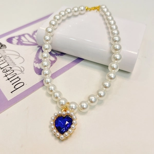 Close-up of pearl pet necklace with blue heart crystal pendant and golden setting